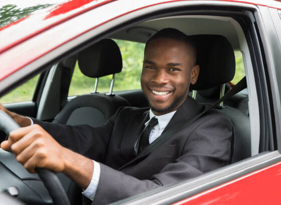 Portrait Of A Happy Young African Businessman Driving Car